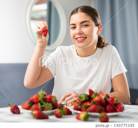 Young woman eating strawberry at home Young woman eating strawberry at home 130775195