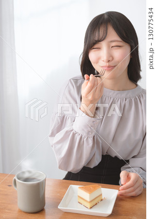美味しそうにケーキを食べる若い女性 美味しそうにケーキを食べる若い女性 130775434