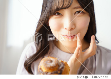 美味しそうにマフィンを食べる若い女性 美味しそうにマフィンを食べる若い女性 130775436