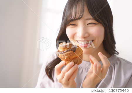 美味しそうにマフィンを食べる若い女性 美味しそうにマフィンを食べる若い女性 130775440