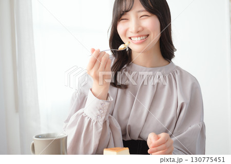 美味しそうにケーキを食べる若い女性 美味しそうにケーキを食べる若い女性 130775451