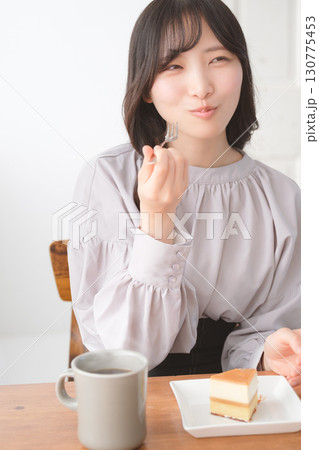 美味しそうにケーキを食べる若い女性 美味しそうにケーキを食べる若い女性 130775453