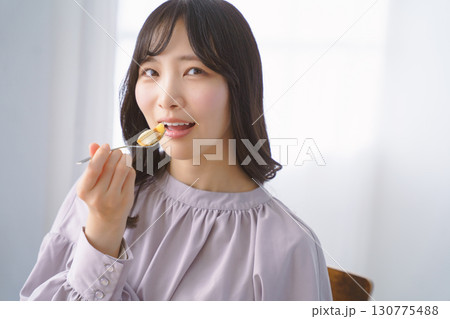 美味しそうにケーキを食べる若い女性 美味しそうにケーキを食べる若い女性 130775488