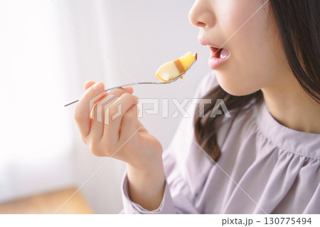 美味しそうにケーキを食べる若い女性 美味しそうにケーキを食べる若い女性 130775494