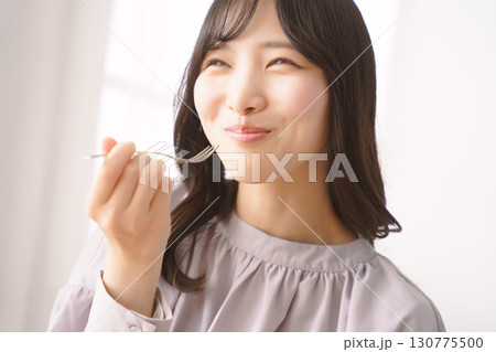 美味しそうにケーキを食べる若い女性 美味しそうにケーキを食べる若い女性 130775500