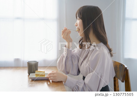 美味しそうにケーキを食べる若い女性 美味しそうにケーキを食べる若い女性 130775505