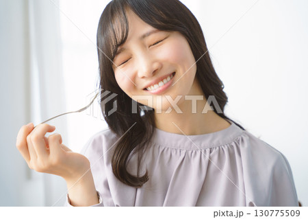 美味しそうにケーキを食べる若い女性 美味しそうにケーキを食べる若い女性 130775509