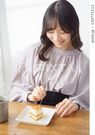 美味しそうにケーキを食べる若い女性 美味しそうにケーキを食べる若い女性 130775512