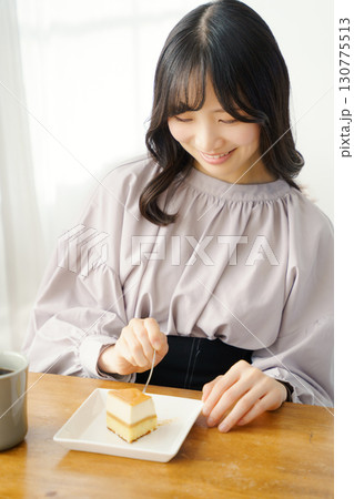 美味しそうにケーキを食べる若い女性 美味しそうにケーキを食べる若い女性 130775513