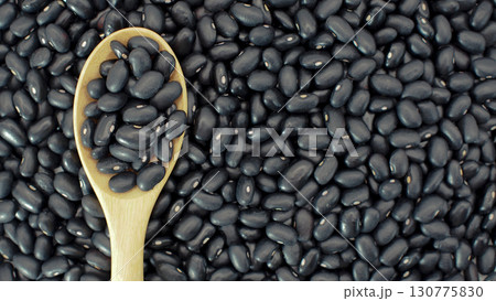 Raw black beans on wooden spoon placed over heap of black beans background. Perfect for illustrating legumes Raw black beans on wooden spoon placed over heap of black beans background. Perfect for illustrating legumes 130775830