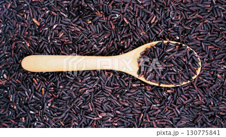 Close-up of riceberry rice grains in a wooden spoon with rice spread across the background, symbolizing organic food, nutrition, and healthy eating Close-up of riceberry rice grains in a wooden spoon with rice spread across the background, symbolizing organic food, nutrition, and healthy eating 130775841