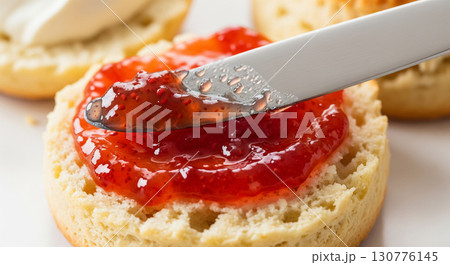 Knife Spreading Strawberry Jam on Fresh Scone 130776145