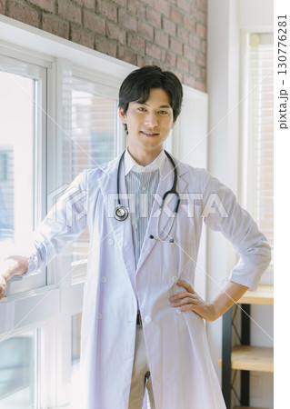 窓辺に立つ白衣を着た若い医師 130776281