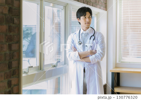 窓辺に立つ白衣を着た若い医師 130776320