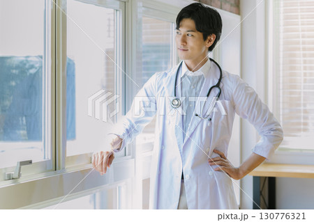窓辺に立つ白衣を着た若い医師 窓辺に立つ白衣を着た若い医師 130776321