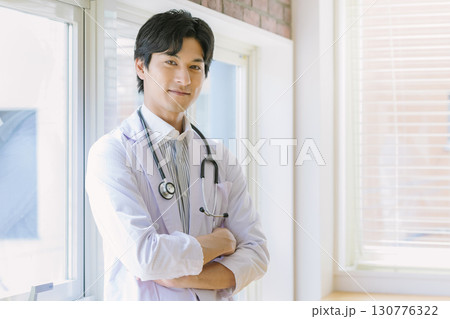 窓辺に立つ白衣を着た若い医師 窓辺に立つ白衣を着た若い医師 130776322