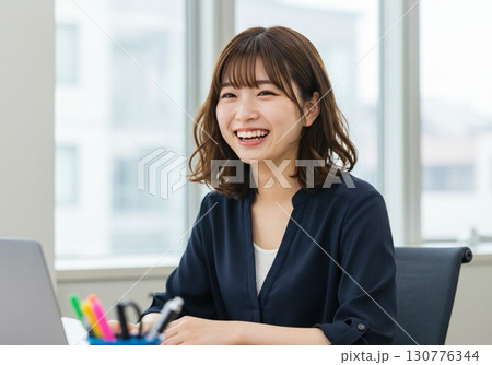 オフィスで笑顔の女性社員｜ビジネス・仕事・キャリア・就活シーンに使える素材写真 130776344