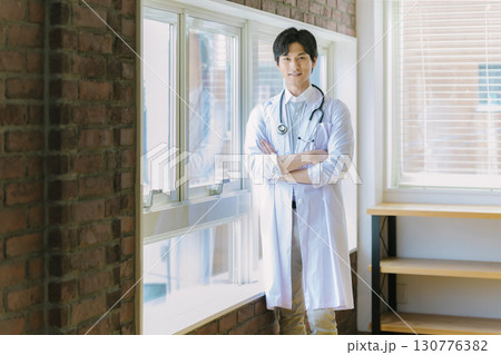 窓辺に立つ白衣を着た若い医師 130776382