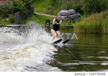 Woman amateur on water ski crosses wave with splashing water Woman amateur on water ski crosses wave with splashing water 130776406