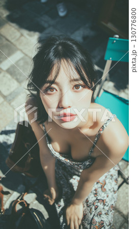 Woman in floral dress enjoying a sunny day while seated outdoors at a bustling city location Woman in floral dress enjoying a sunny day while seated outdoors at a bustling city location 130776800