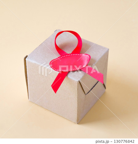 Brown Box with red ribbon on a color background. 130776842