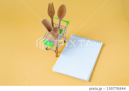 Wood spoon and fork in shopping cart on background. Wood spoon and fork in shopping cart on background. 130776844