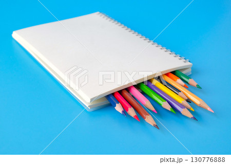 A notepad with color pencil on background.A notepad with color pencil on background. 130776888
