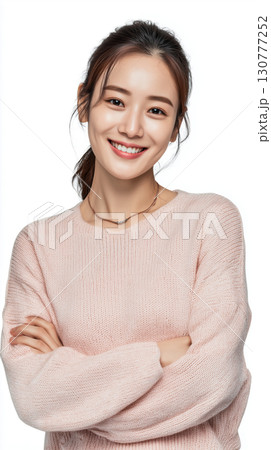 Smiling young Asian woman in cozy sweater poses confidently with crossed arms 130777252