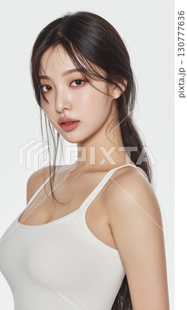 Young Korean woman in casual attire poses for a portrait with a gentle expression and flowing hair 130777636