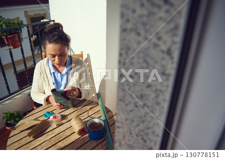 Woman Wrapping Gift Outdoors on Wooden Table with Craft Materials Woman Wrapping Gift Outdoors on Wooden Table with Craft Materials 130778151