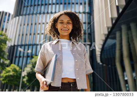 A Cheerful Woman Working Remotely on Her Laptop in a Beautiful and Lively Urban Setting A Cheerful Woman Working Remotely on Her Laptop in a Beautiful and Lively Urban Setting 130780033