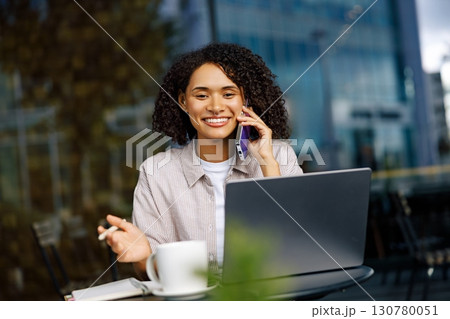 A Young and Ambitious Professional Engaging in Remote Work Using a Laptop and Phone A Young and Ambitious Professional Engaging in Remote Work Using a Laptop and Phone 130780051
