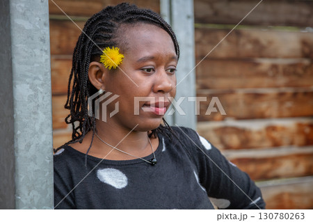 Thoughtful African American Woman with Yellow Flower in Hair Wearing Polka Dot Top Thoughtful African American Woman with Yellow Flower in Hair Wearing Polka Dot Top 130780263