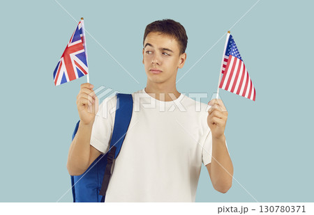 Boy student holding the flags of Great Britain and United States of America on a blue background. Boy student holding the flags of Great Britain and United States of America on a blue background. 130780371