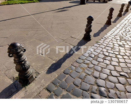 Artistic Guardrails Casting Elongated Shadows on a Cobblestone Street in the Warm Afternoon Light 130780657