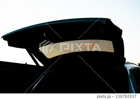 The open trunk of a car is silhouetted, reflecting the sunset sky. An open car trunk silhouette against the sky, capturing the intricate details of the vehicle and its surroundings in a moody setting. The open trunk of a car is silhouetted, reflecting the sunset sky. An open car trunk silhouette against the sky, capturing the intricate details of the vehicle and its surroundings in a moody setting. 130782037