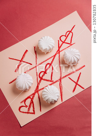 Romantic tic-tac-toe game with white marshmallows and red hearts on pink background Romantic tic-tac-toe game with white marshmallows and red hearts on pink background 130782835