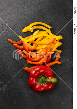 Sliced red and yellow bell peppers with whole pepper on black background, healthy food concept 130782836