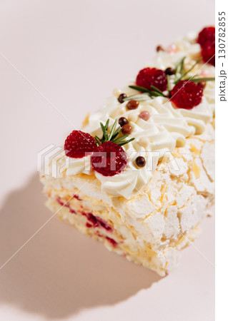 Meringue roulade with raspberries and cream on pastel pink background, top dessert macro Meringue roulade with raspberries and cream on pastel pink background, top dessert macro 130782855