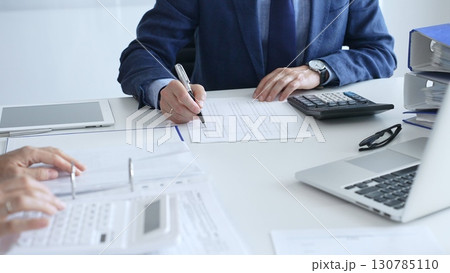Close up of female accountant hands using calculator while collaborating with male colleague in office, calculating taxes and analyzing financial data. Audit and taxes in business Close up of female accountant hands using calculator while collaborating with male colleague in office, calculating taxes and analyzing financial data. Audit and taxes in business 130785110