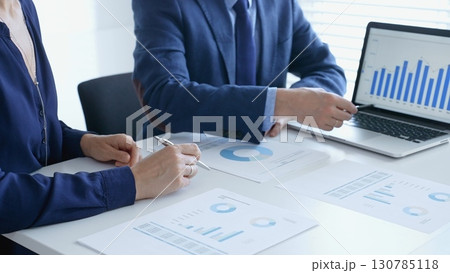 Business professionals reviewing financial data, pointing at laptop charts and shared documents during collaborative strategy session. Business people and finance concept Business professionals reviewing financial data, pointing at laptop charts and shared documents during collaborative strategy session. Business people and finance concept 130785118