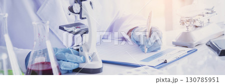 Banner Asian woman scientist hand write note research in medical lab look at science microscope. Panorama biology chemistry lab. Asian Female technician laboratory using microscope with copy space Banner Asian woman scientist hand write note research in medical lab look at science microscope. Panorama biology chemistry lab. Asian Female technician laboratory using microscope with copy space 130785951