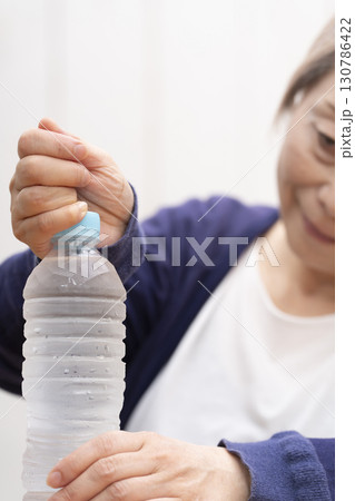 ペットボトルのキャップを開けるシニア女性 ペットボトルのキャップを開けるシニア女性 130786422