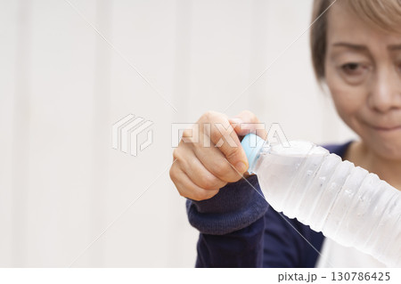 ペットボトルのキャップを開けるシニア女性 130786425