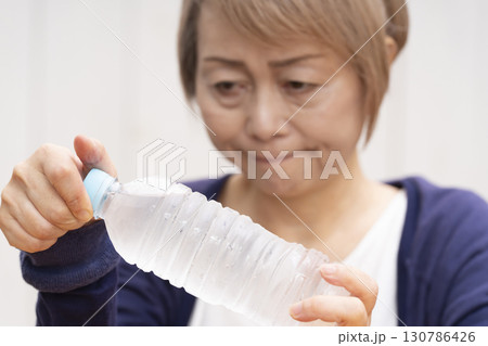 ペットボトルのキャップを開けるシニア女性 130786426