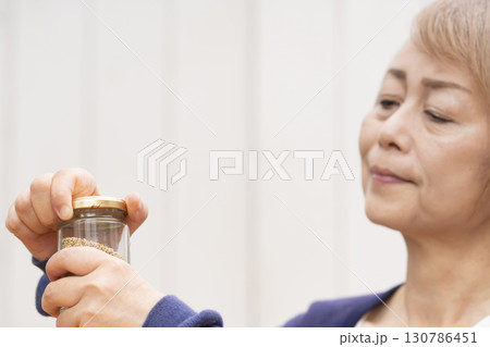 瓶の蓋を開けるシニア女性 130786451