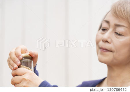 瓶の蓋を開けるシニア女性 130786452