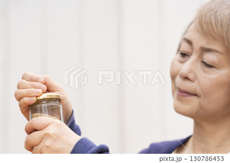 瓶の蓋を開けるシニア女性 130786453