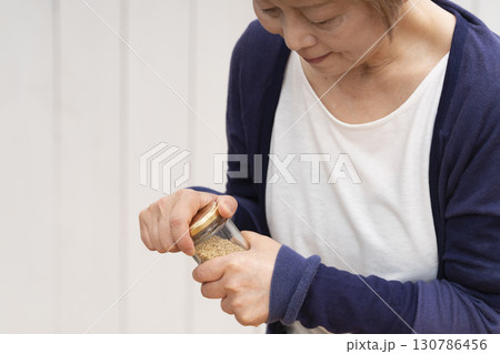 瓶の蓋を開けるシニア女性 130786456