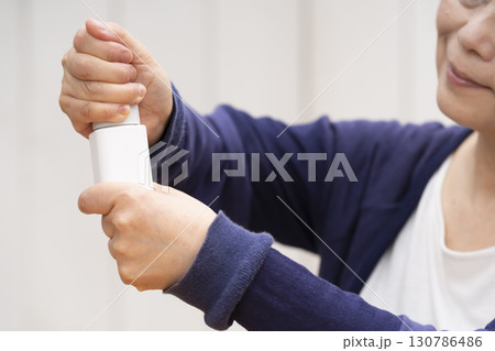 薬の瓶の蓋を開けるシニア女性 130786486